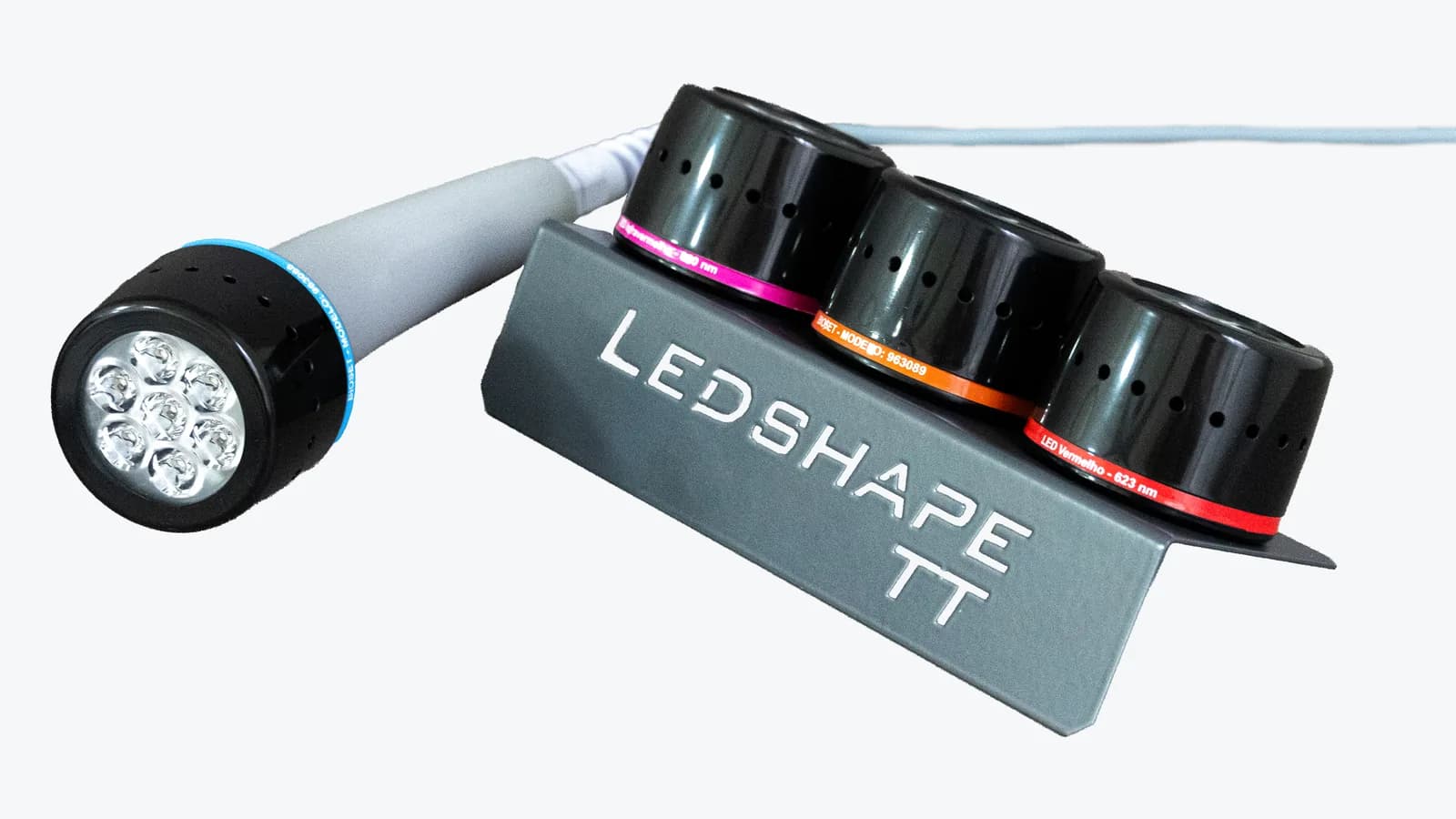 Peça de mão do Ledshape TT com ponteira de anel azul ao lado do suporte com as ponteiras de anéis rosa, laranja e vermelho