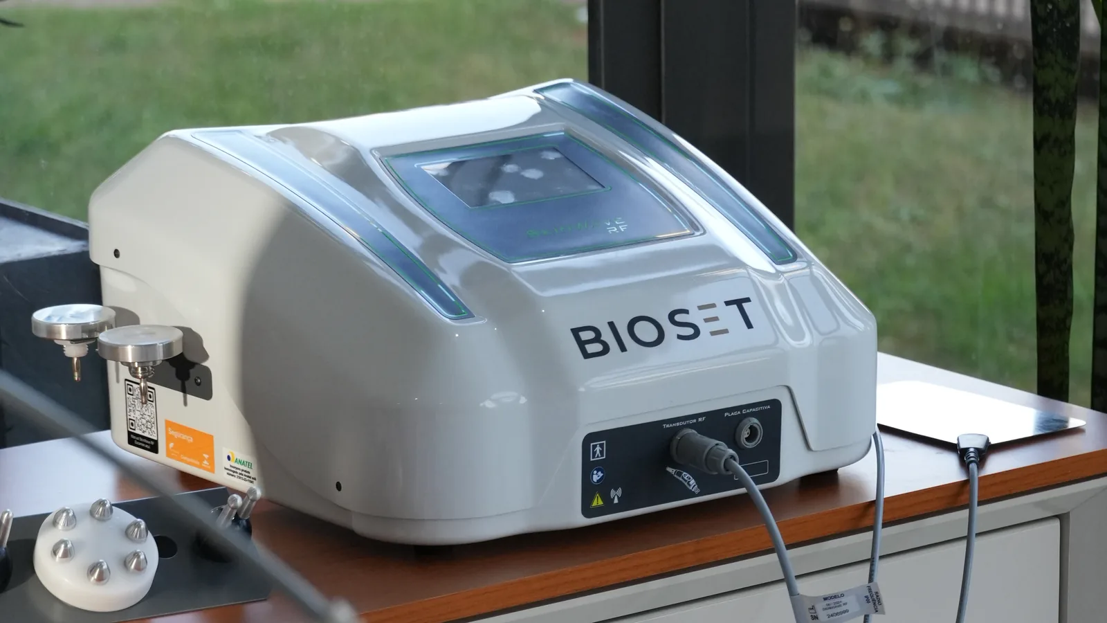 Skinwave RF sobre bancada de clínica diante de uma janela, com a marca Bioset na frente, eletrodos no suporte e etiquetas na lateral
